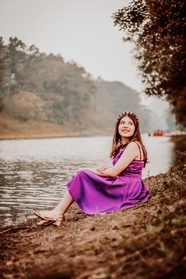 坐在河边的紫色连衣裙美女图片