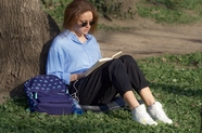 户外草地靠在树边看书的美女图片