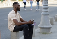 非洲男人坐在街头石墩上听音乐图片