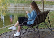 坐在河边椅子上刷手机的美女图片