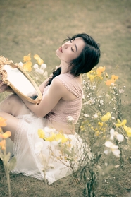 坐在草地上手持铜镜的亚洲美女图片