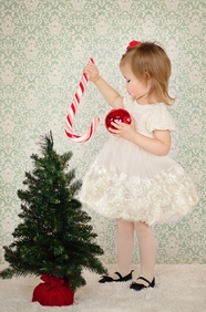 小女孩站在圣诞树旁玩耍图片