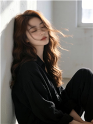 倚靠在墙角的长卷发黑色衬衫美女图片